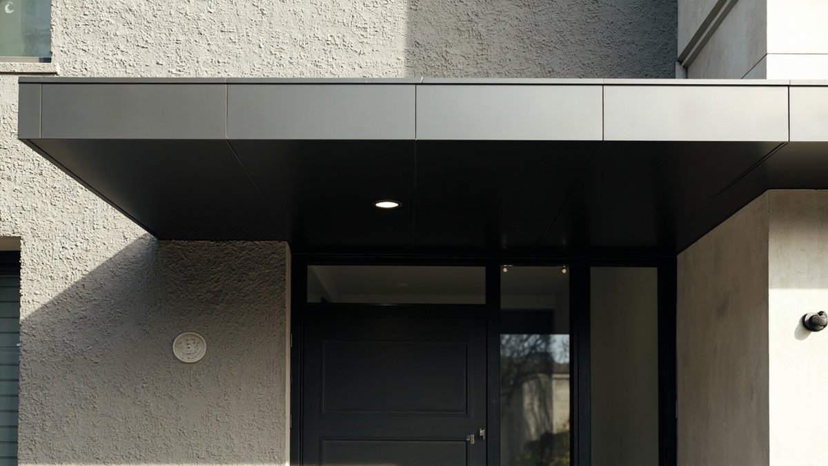 Charcoal flat ACP canopy with a downlight above the main door of a modern terrace house