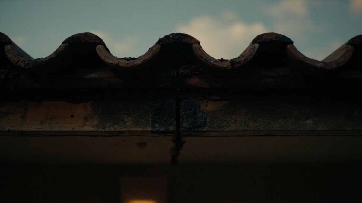 Small gap under the first row of roof tiles at the eaves of a house at dusk