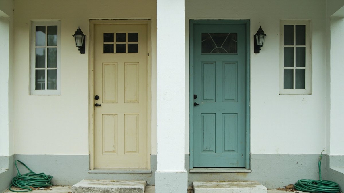 Two matching front doors of a semi-detached house represent co-ownership of property in joint names.