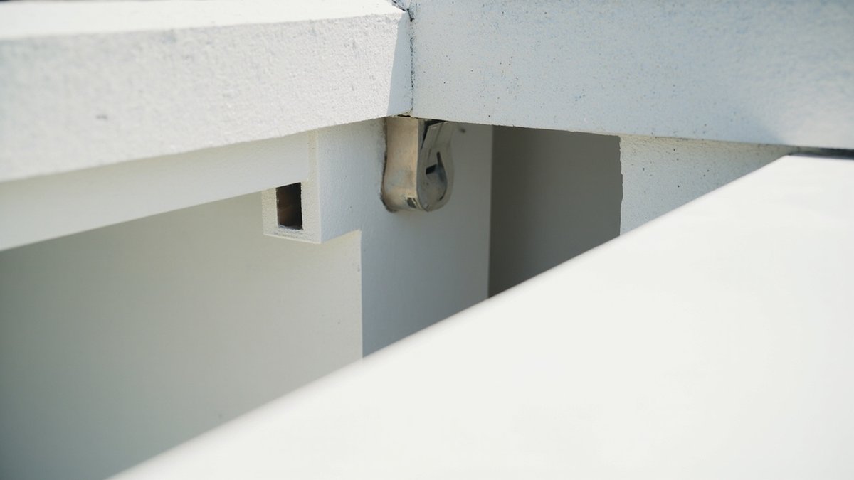 Hidden metal box gutter behind a white parapet wall with an outlet and an overflow spout