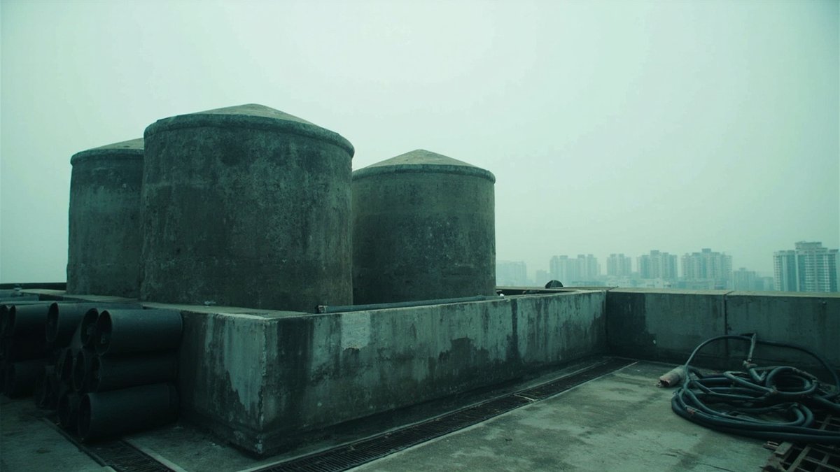 Condominium rooftop water tanks beside stacked waterproofing membrane rolls