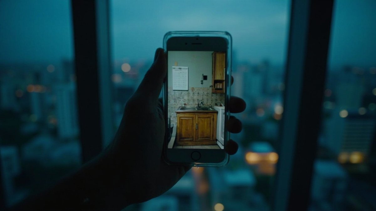 Phone video call showing a parent's tidy old kitchen with a calendar and key hook