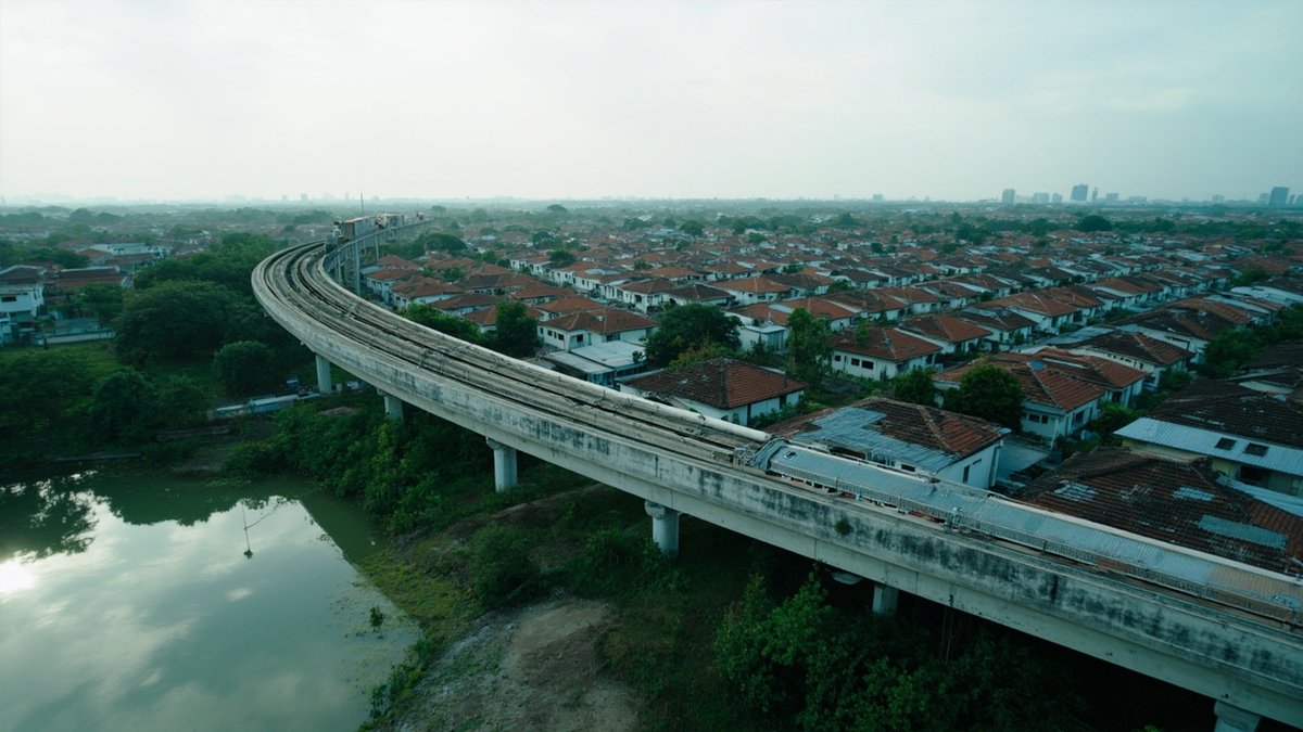 An aerial suburb view with an LRT track represents choosing a property location by transport access.