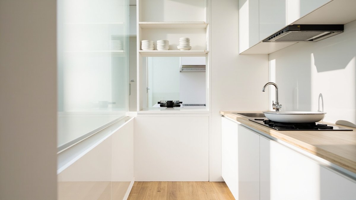 Ilustrasi konsep reka bentuk: dapur kondo gaya muji yang padat dengan pintu rata putih, table top kayu cerah, sinki kecil dan rak terbuka berisi mangkuk putih