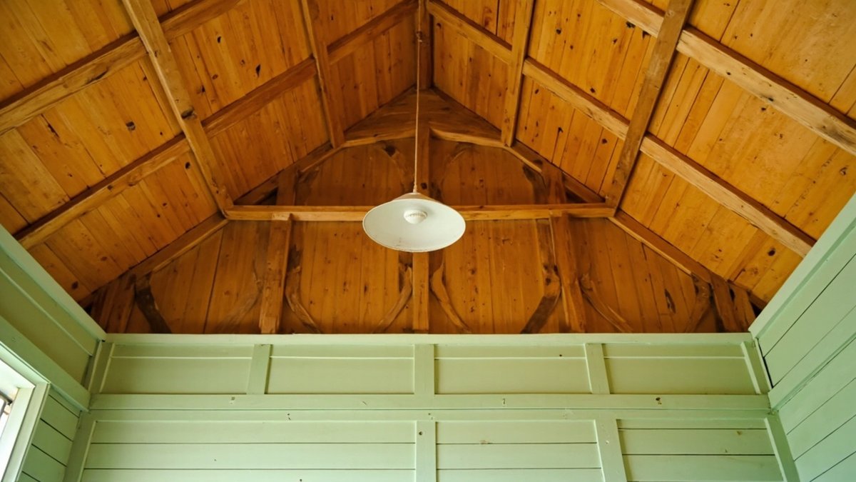 Illustrative concept design: pitched ceiling of varnished timber boards with a white pendant light above pale green plank walls
