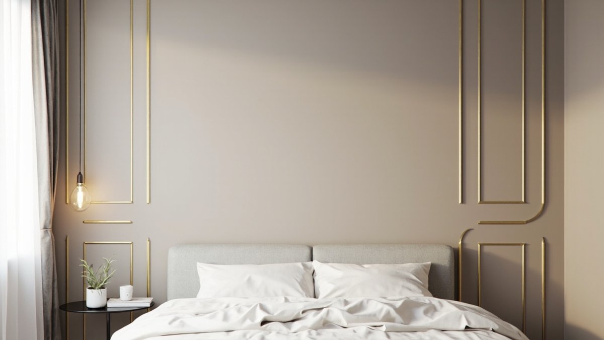 Illustrative concept design: greige wall with thin gold moulding frames behind a grey upholstered bed