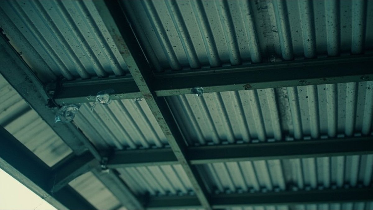 Water droplets forming along the purlins under a metal porch roof in the morning