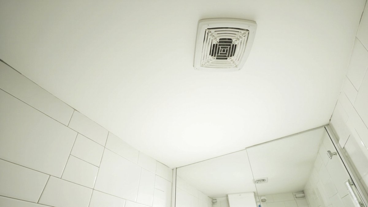 Illustrative concept design: plain white square exhaust fan grille in a white bathroom ceiling above white tiles