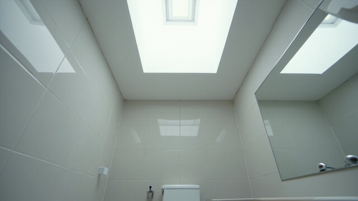 Illustrative concept design: large skylight well bringing daylight into a white-tiled bathroom