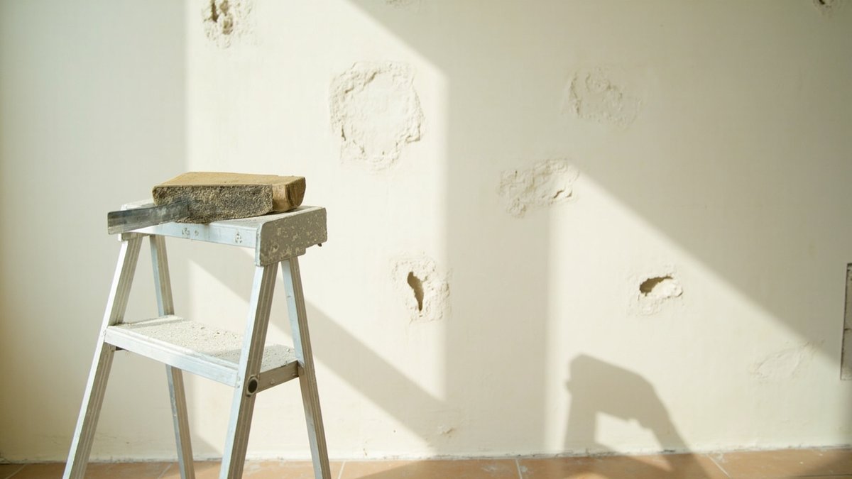 Filled and sanded patches on a wall where an old TV bracket was removed, ready for primer