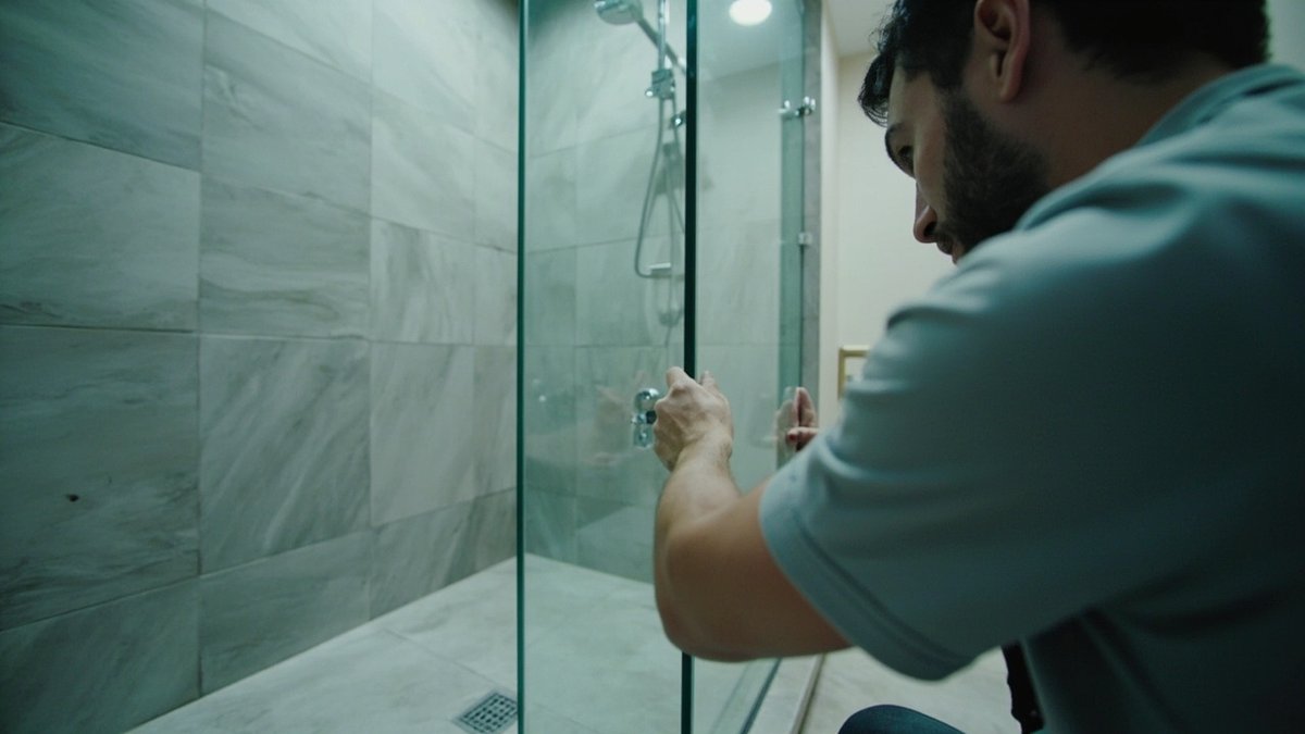 Installer fitting a frameless shower screen in a mid-rise condominium bathroom in Sungai Besi