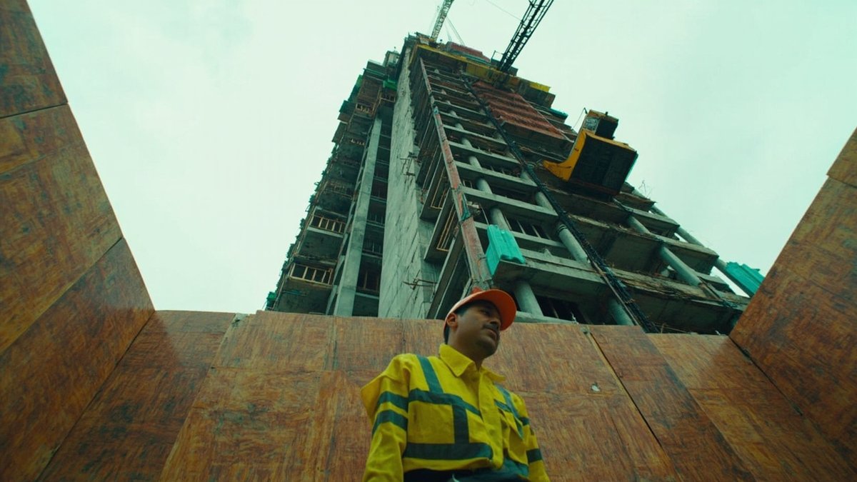 Contractor hoarding and enclosed debris chute rising up the side of a condo