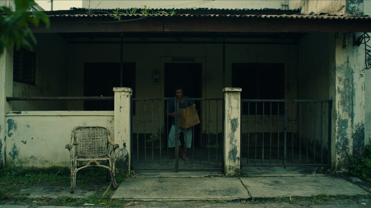 Owner carrying the last box out of an emptied older terrace house after selling