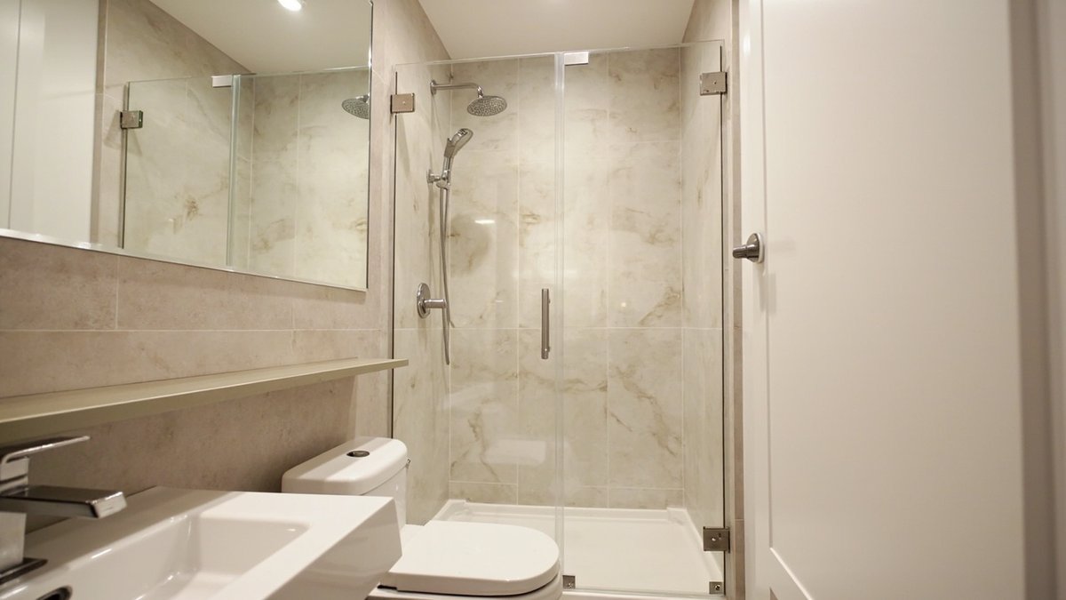 Illustrative concept design: semi-frameless glass shower panel and hinged door with chrome clamps in a beige marble-look condo bathroom
