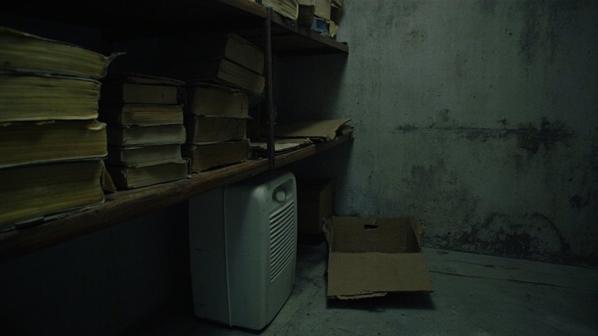 Damp storeroom shelf with old books and a dehumidifier in a Malaysian terrace house