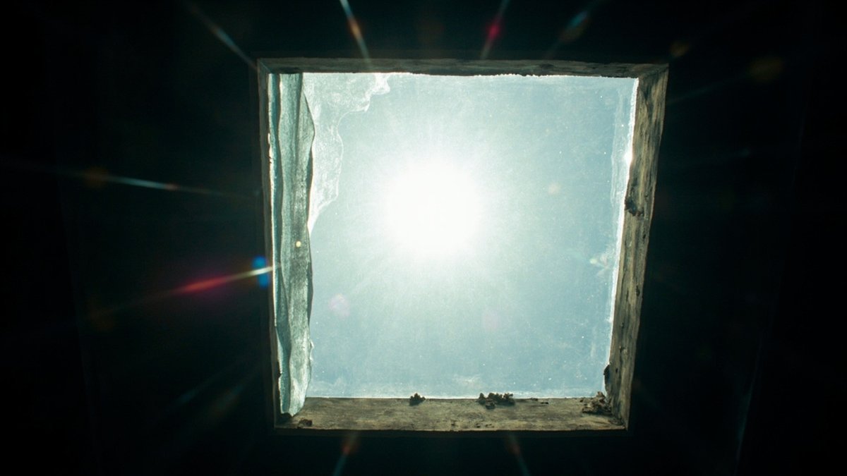 Looking up at a skylight with harsh midday sun, half covered by heat-reflective film