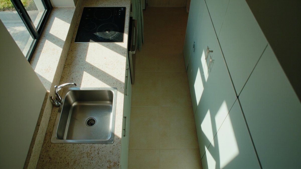 Narrow galley kitchen with sage-green cabinets and a tall pantry unit, seen from above