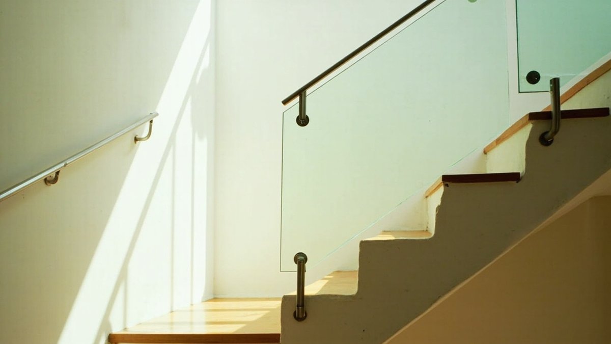 Staircase with a frameless glass balustrade and stainless handrail in a terrace house
