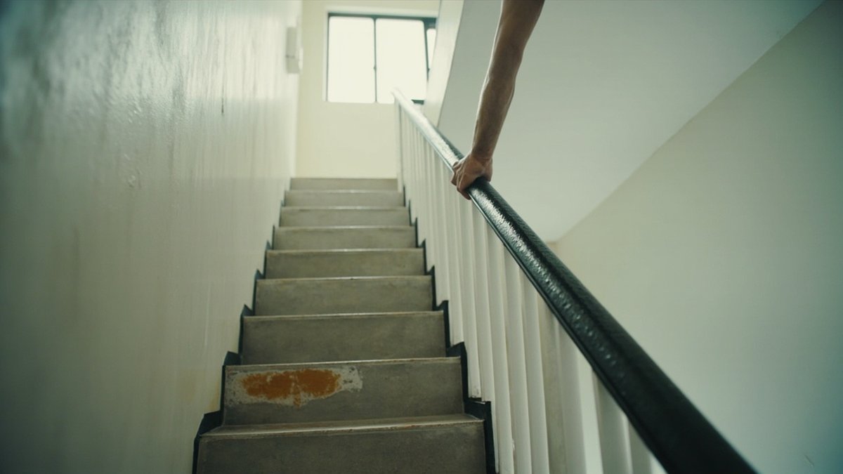 Tiled staircase in a new terrace house with a steel railing, a chipped nosing and a rust spot at a weld