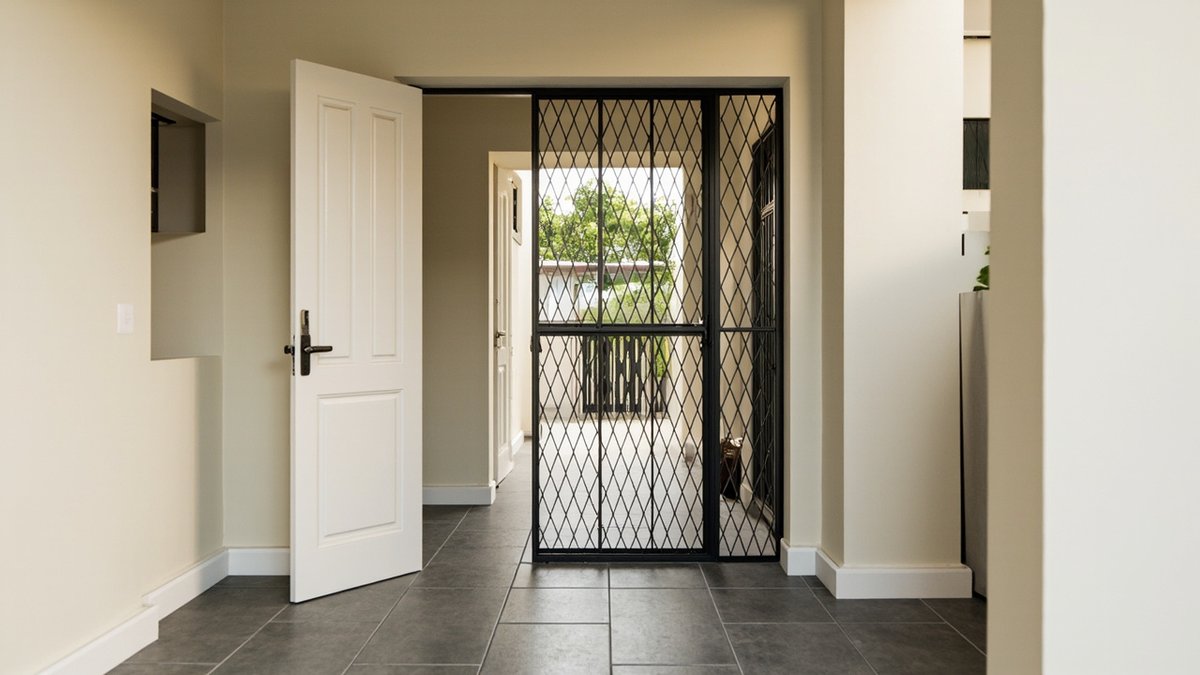 Illustrative concept design: black diamond-pattern folding trellis grille closed across a back doorway, the white door open beside it