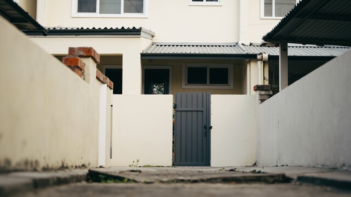 Illustrative concept design: rear of a terrace row from the back lane, metal lean-to yard roofs set just below the upstairs windows, grey back gate in the rear wall