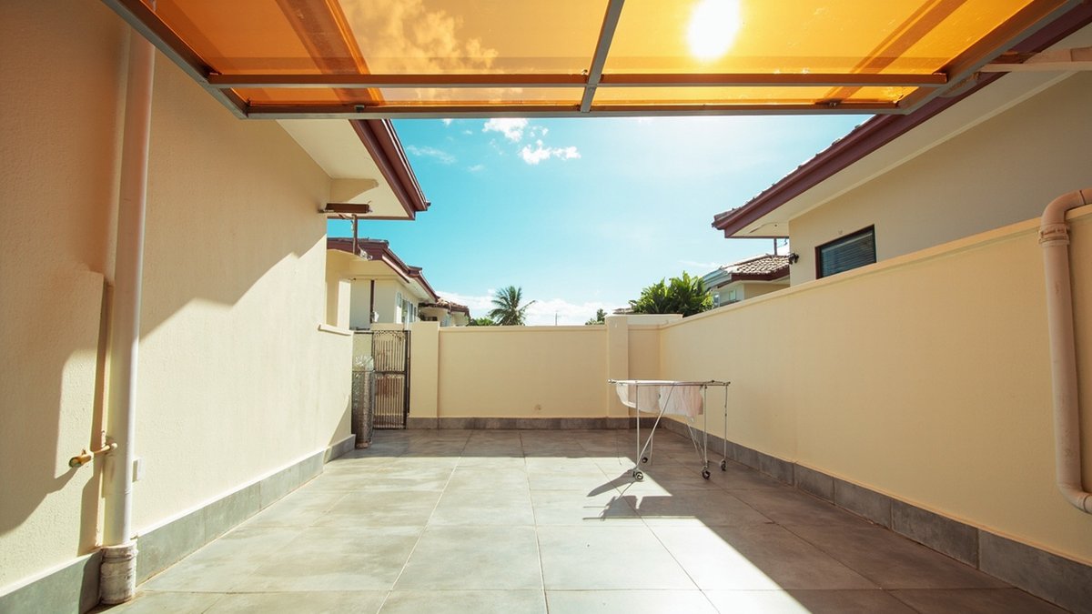 Illustrative concept design: translucent orange roof covering half a back yard, the rear half open to the sky with a drying rack of towels in the sun
