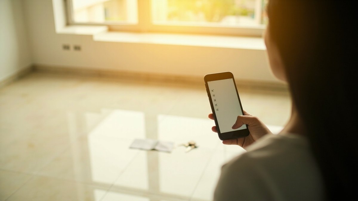 Homeowner ticking a defect checklist on a phone in an empty new condo