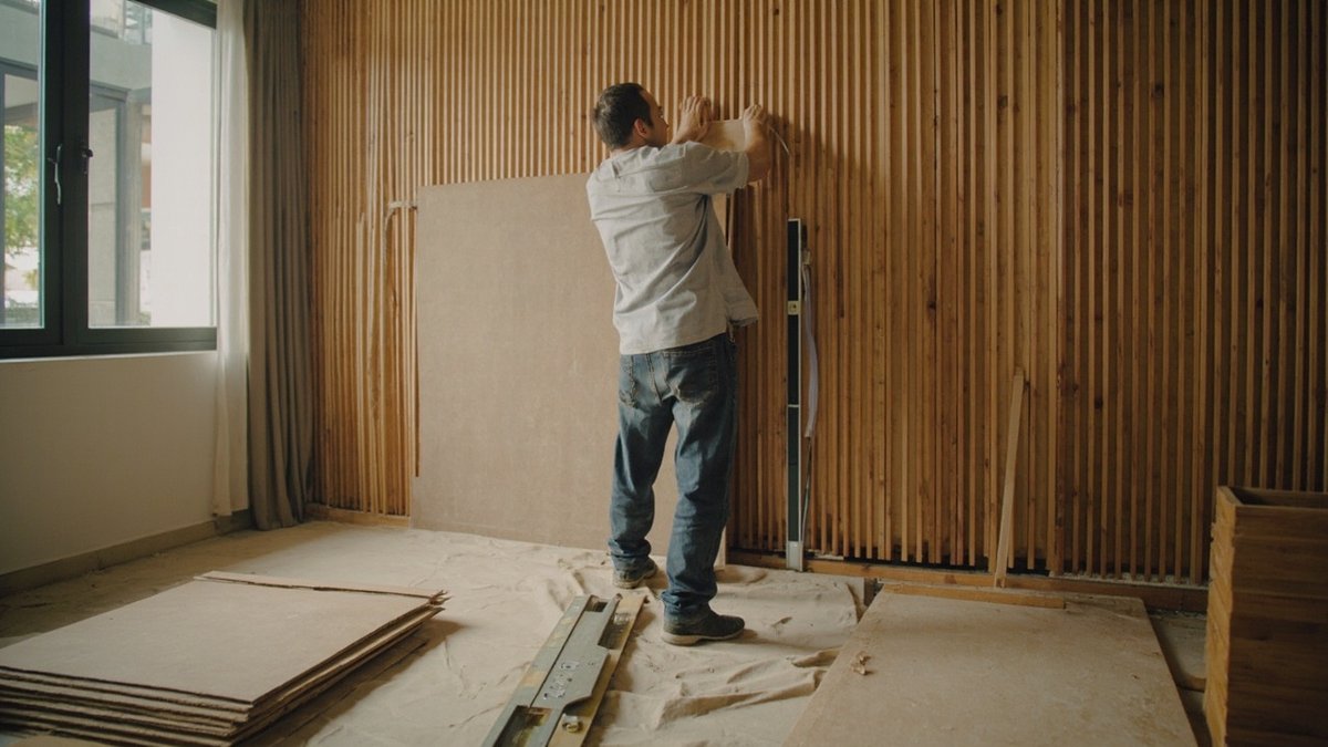 Installer fixing fluted wall panels onto timber battens in a living room