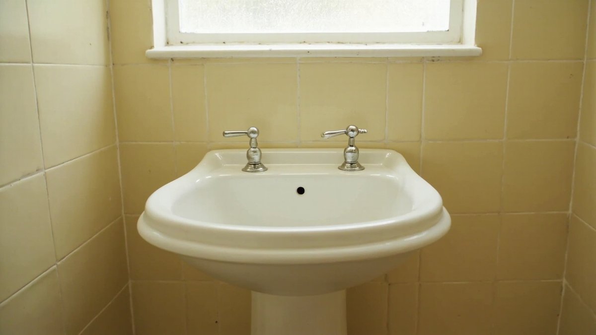 Illustrative concept design: white pedestal basin with chrome pillar taps against pale butter yellow wall tiles