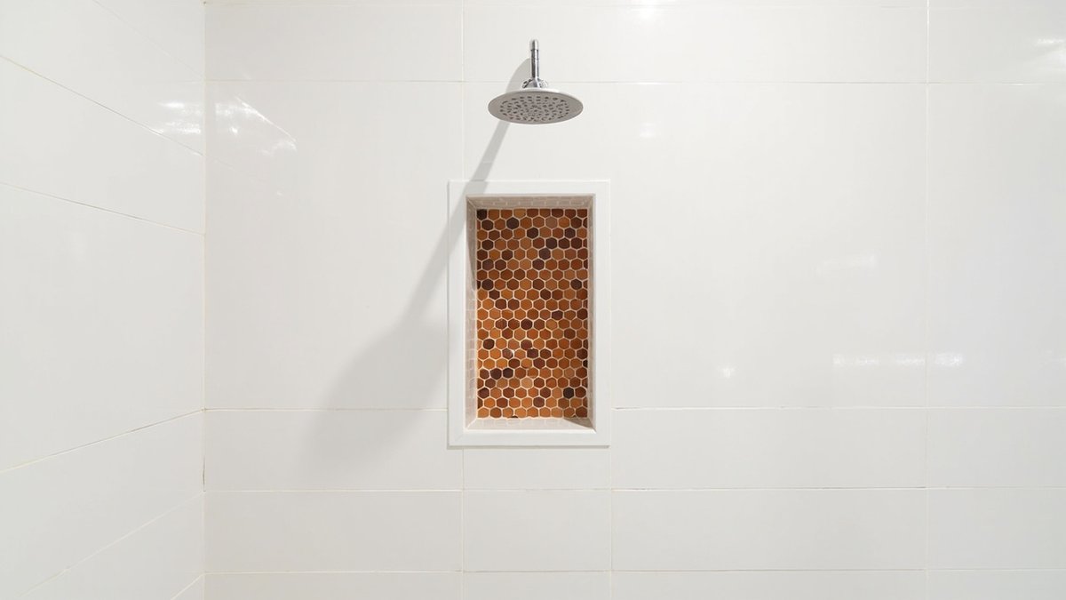 Illustrative concept design: tall shower niche with a terracotta hexagon mosaic back in a white tiled wall